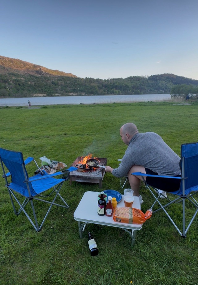 Craig cooking at a campfire beside a lake